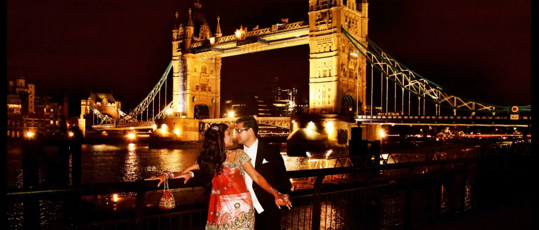 Bride and groom in front of Tower Bridge lit up at night