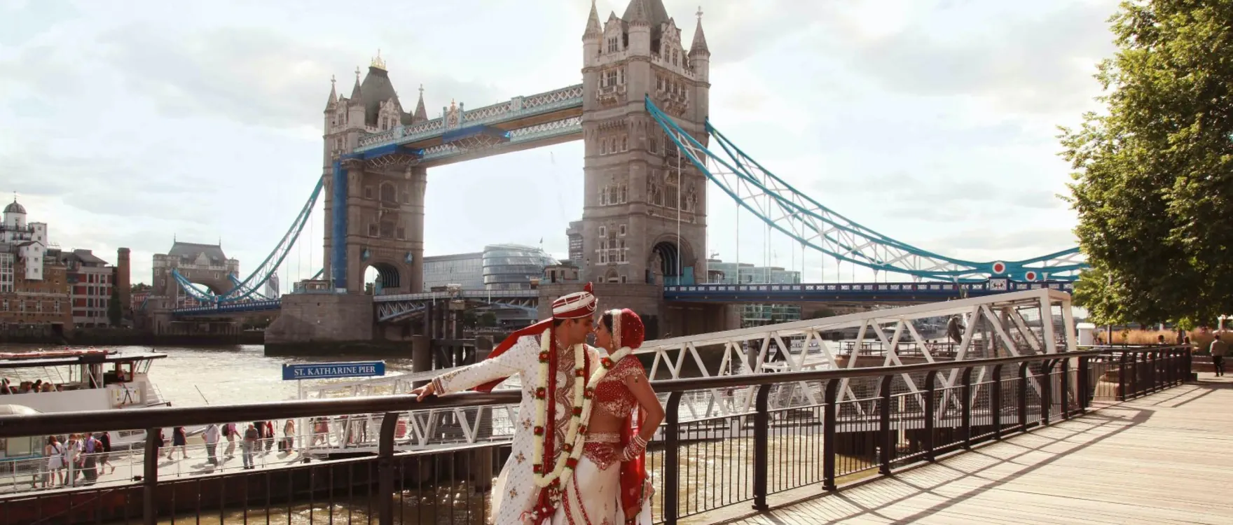 Bride and groom in red and cream in front of Tower Bridge