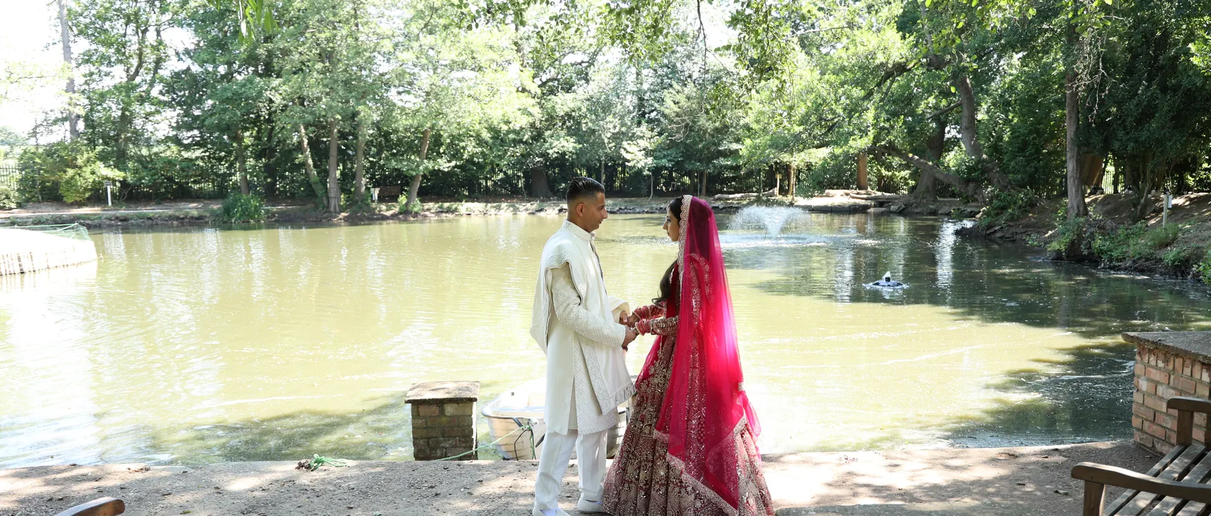 Bride and groom photographed at a distance beside a lake