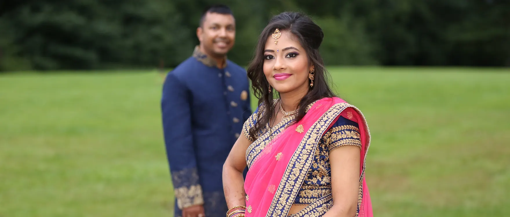 Bride in a pink sari with her groom in an open field