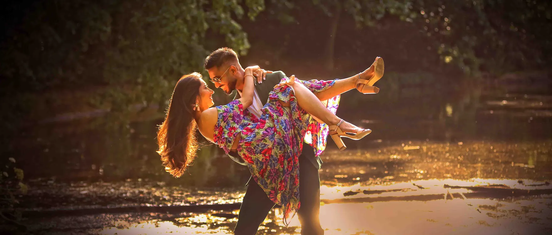 Groom carrying his bride through shallow water at golden hour