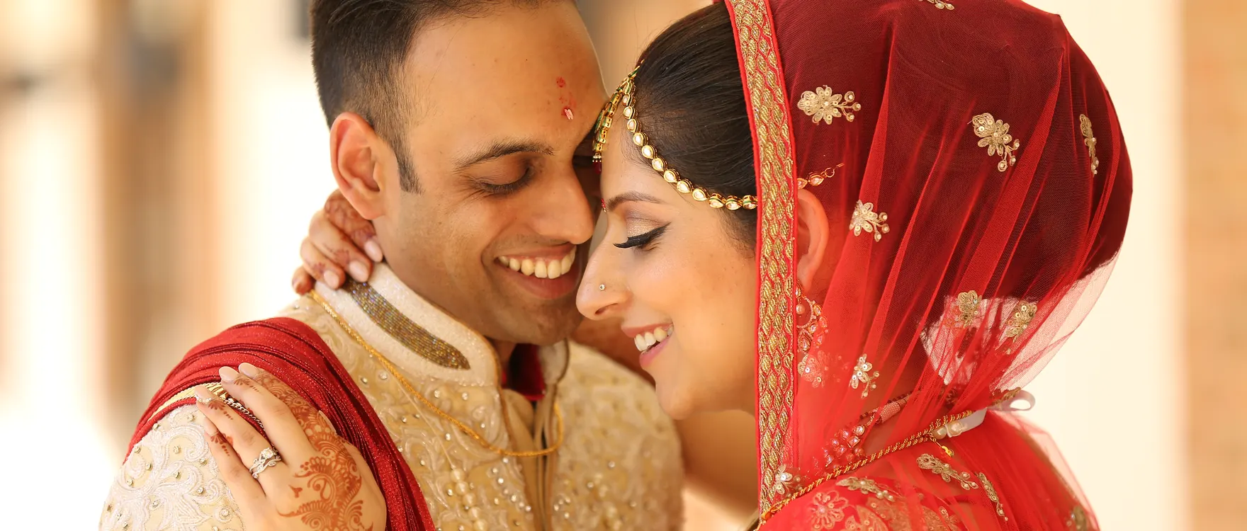 Bride and groom together, bride beneath a red veil