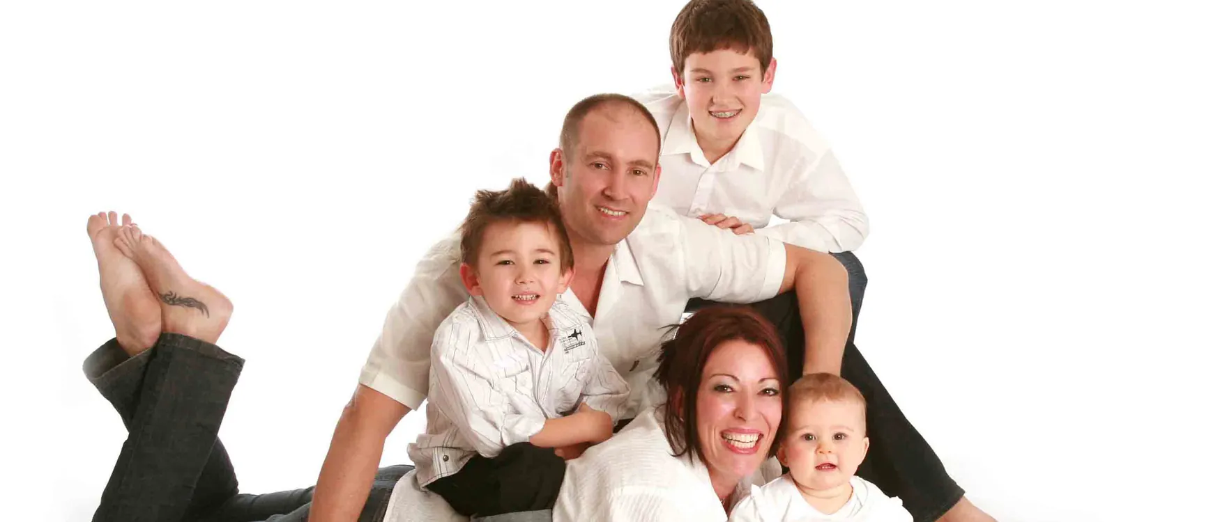 Family of five in white shirts lying together on the studio floor