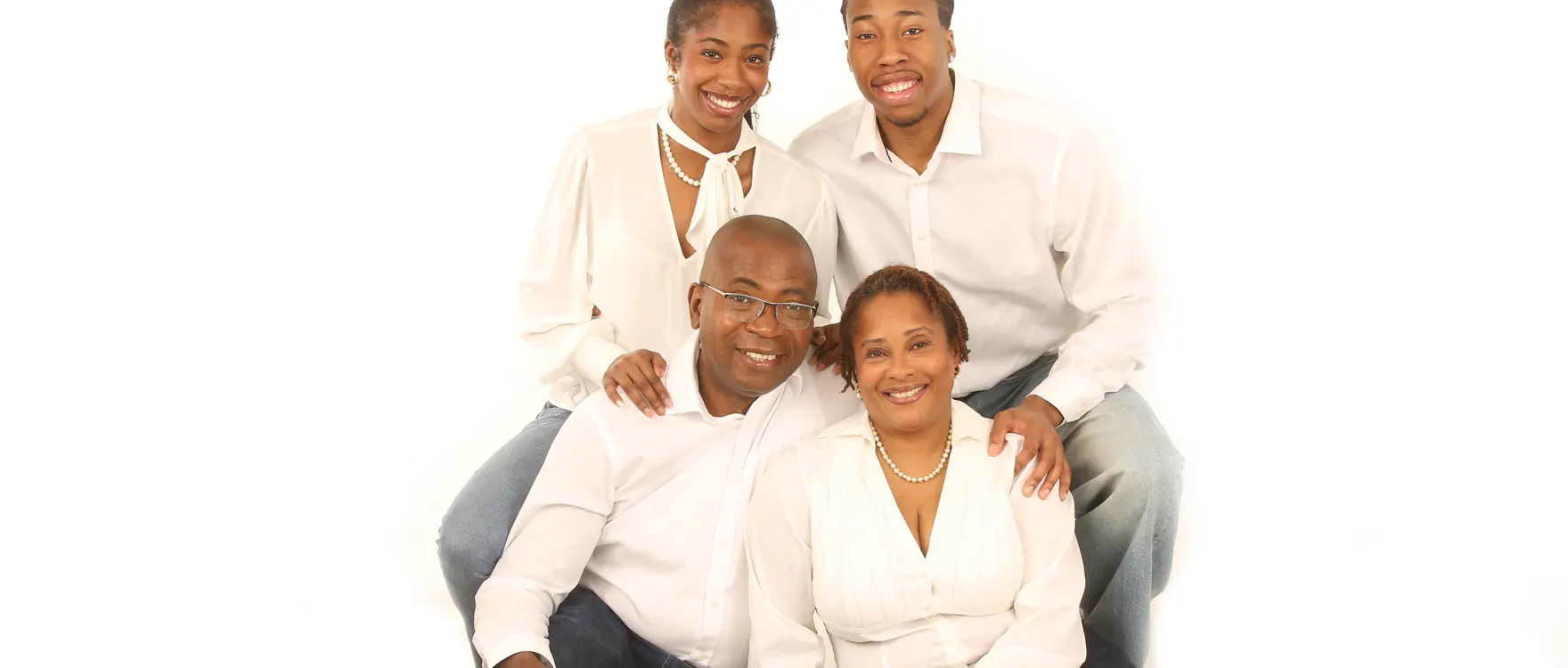 Family of four in white shirts and jeans seated on the studio floor