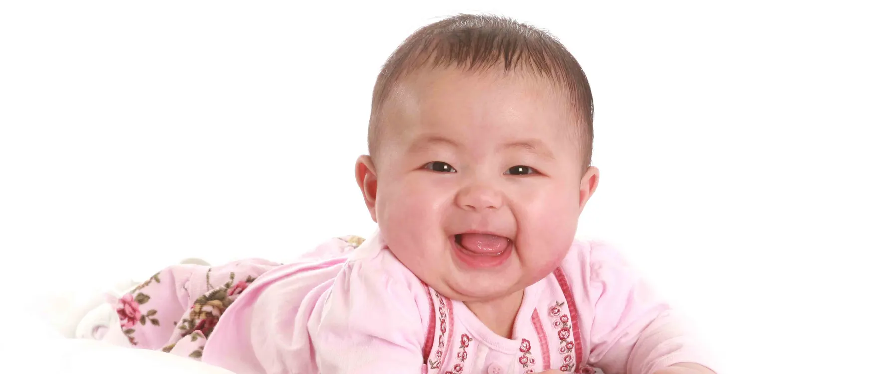 Baby in pink lying on her front, laughing