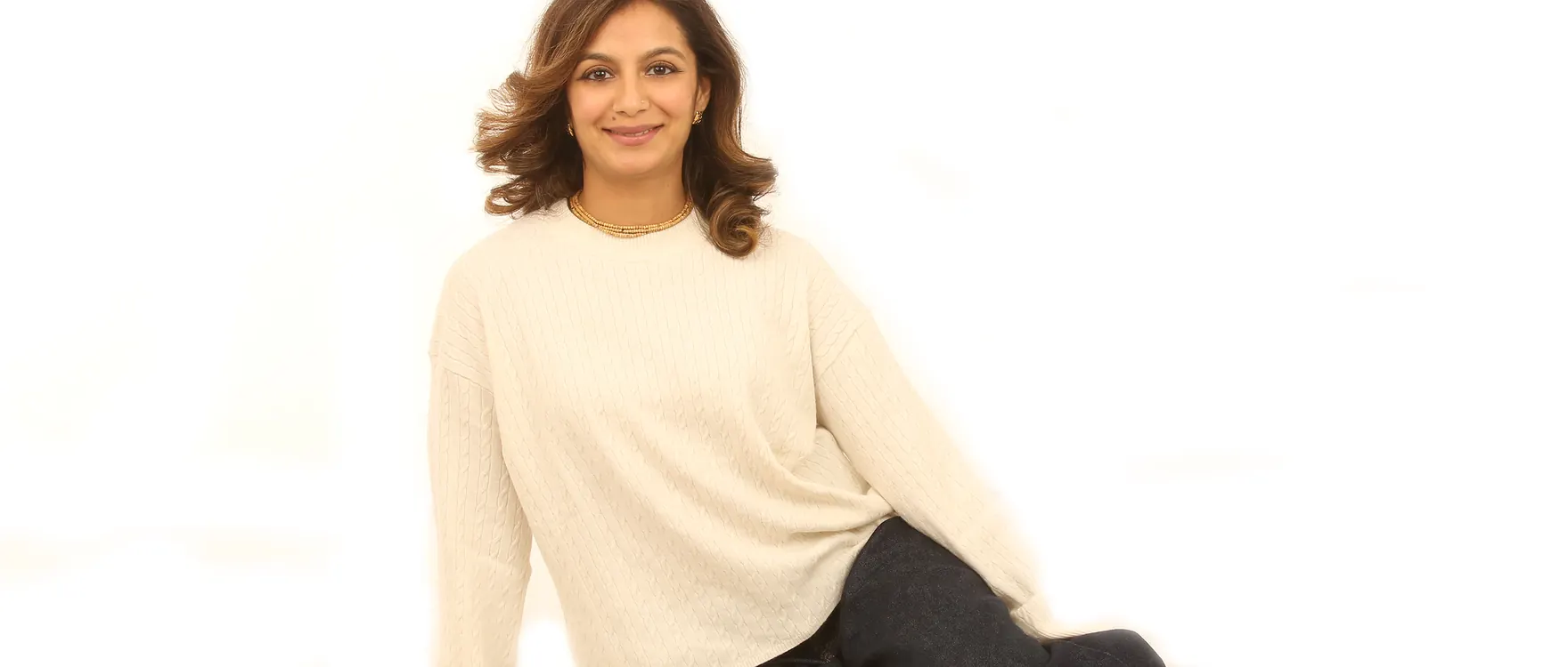 Woman in a cream jumper seated on the studio floor