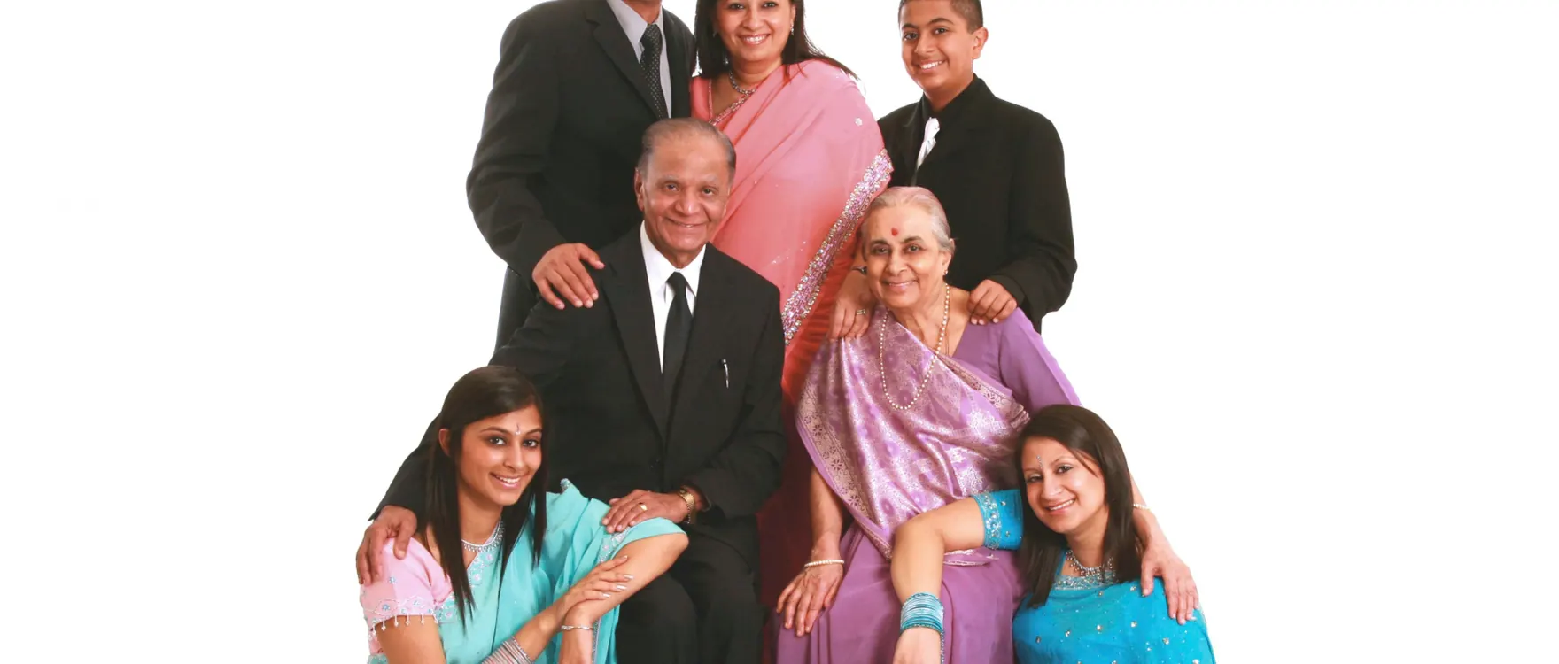 Three-generation family in saris and suits, studio group portrait