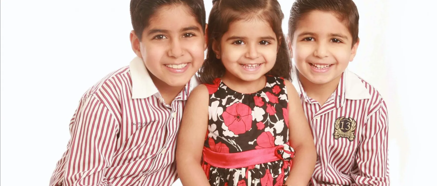 Three children in striped shirts and a floral dress, studio portrait