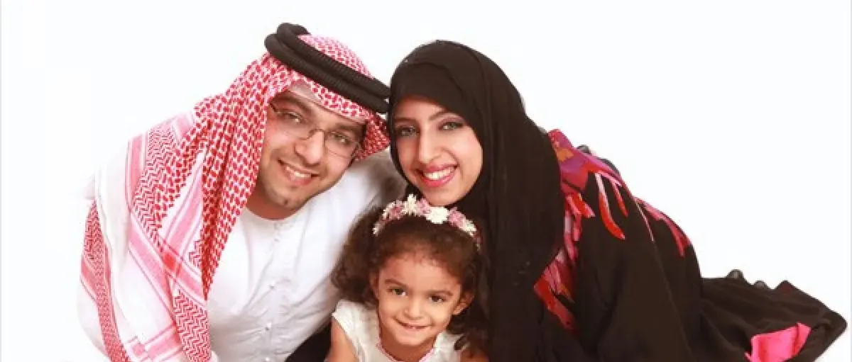 Parents in traditional Gulf dress with their young daughter, studio portrait