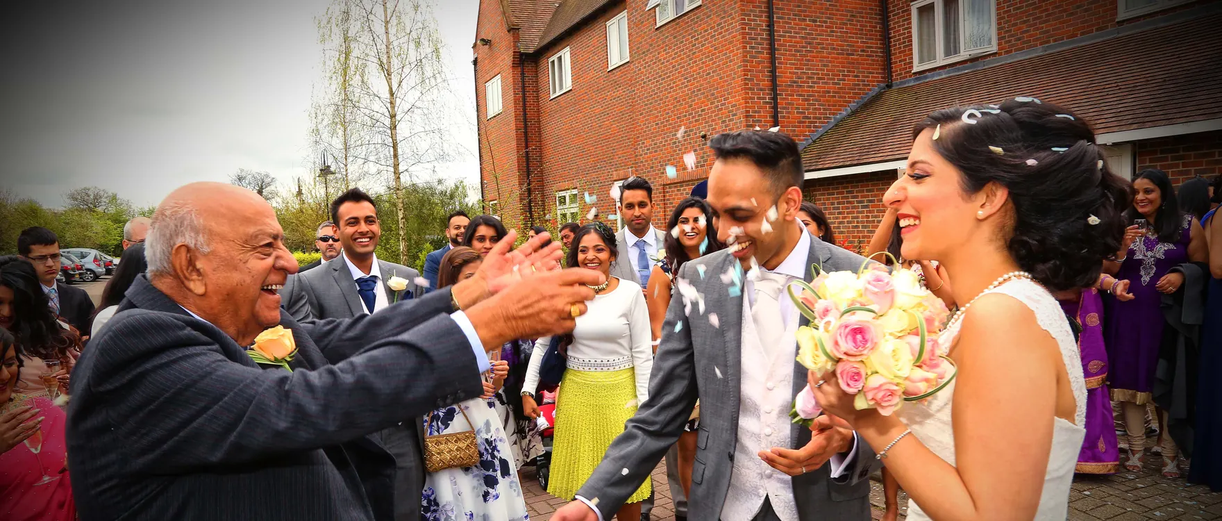 Bride and groom showered with confetti by guests outside the venue